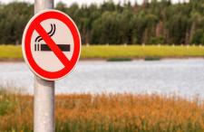 No smoking sign outdoors in front of a lake