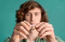 A teenager breaking a cigarette in half