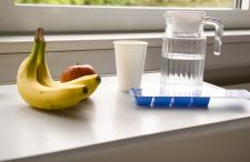 A pitcher of water, a banana and an apple on a hospital room table