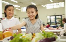 Two girls getting food in a cafeteria line