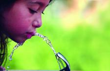 Child drinking from a water fountain outside