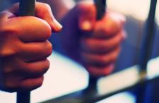 A pair of hands around jail cell bars