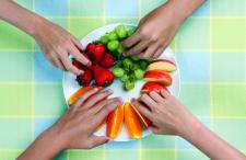 Hands reaching for fruit on a plate