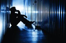 Adolescent sitting in a dark detention facility