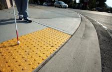 Person using a white cane to enter the designated crosswalk